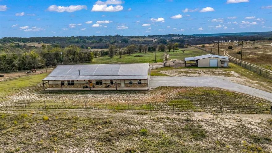 Authentic ranch living meets modern comfort in this 4-bedroom, 2.5-bath barndominium set on 17.8± unrestricted acres in Parker County. Stained concrete floors paired with custom wood and rock work anchor the open-concept living area, creating a true Western feel. The kitchen is built for everyday use, featuring a large island, abundant storage, and thoughtful functional design. The primary suite offers a private en-suite bath, while the additional bedrooms provide plenty of space for family or guests. Outside, the land is ready for your livestock, horses, or equipment with a versatile shop, covered awning, and a dedicated riding pad for your equestrian needs. Wide-open acreage offers room to roam and ride. Located just minutes from Weatherford’s dining, shopping, and entertainment, this property delivers the peace of country living without sacrificing convenience. A rare opportunity to own a functional, country estate in a highly desirable area.