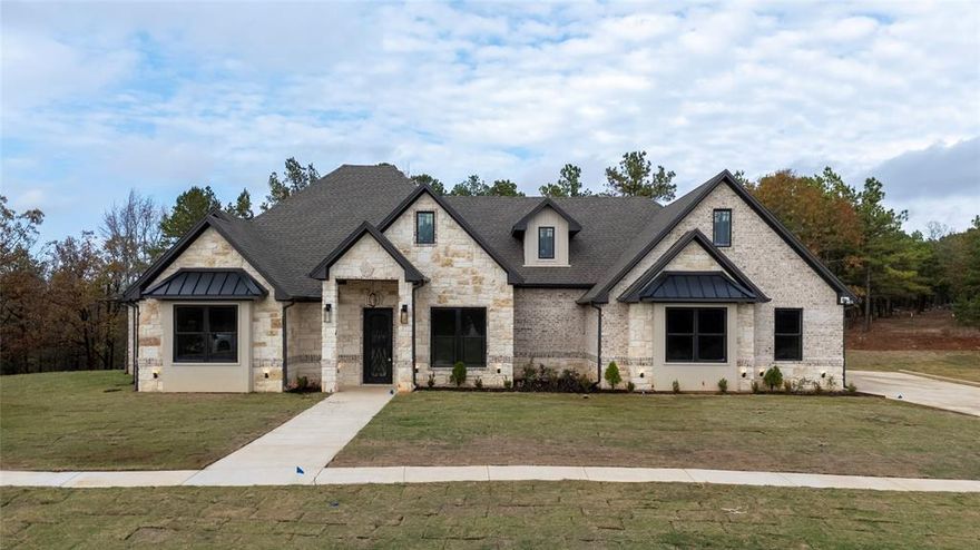 Welcome to luxury living in the highly sought-after Cypress Ridge community of Lindale, Texas! This brand-new 2,578 sq ft construction offers a flawless blend of comfort, elegance, and thoughtful design—truly built to impress from the moment you arrive. The exterior boasts a striking mix of brick, stone, and refined stucco accents, giving the home unforgettable curb appeal.
Step inside and you’ll be greeted by a grand foyer with a beautiful combination of ceramic tile and luxury vinyl plank flooring. The open-concept living area centers around a stunning fireplace—gas-ready and perfect for cozy winter nights. The chef’s kitchen delivers both style and function with quartz countertops, stainless steel appliances, a hidden pantry, built-ins, a mini fridge, and even a dedicated ice maker.
The master retreat is a peaceful sanctuary featuring a detailed box ceiling, an oversized soaking tub, a walk-in tile shower with multiple showerheads, double vanities, and a spacious walk-in closet. On the opposite side of the home, an in-law suite with its own full bath offers privacy and comfort for extended stays or overnight guests. Working from home? The dedicated office with custom built-ins provides the perfect setting for productivity or quiet reading.
Step outside and enjoy an entertainer’s dream—an expansive covered patio complete with an outdoor kitchen featuring granite countertops, a wine cooler, gas grill, and ample space to gather, dine, and relax year-round. Additional highlights include a 3-car garage, 4 total bedrooms, 3.5 baths, and premium finishes throughout.
This home truly has it all—luxury, functionality, location, and an exceptional community. Don’t miss your opportunity to make it yours. Call your favorite Realtor® today to schedule a private tour!