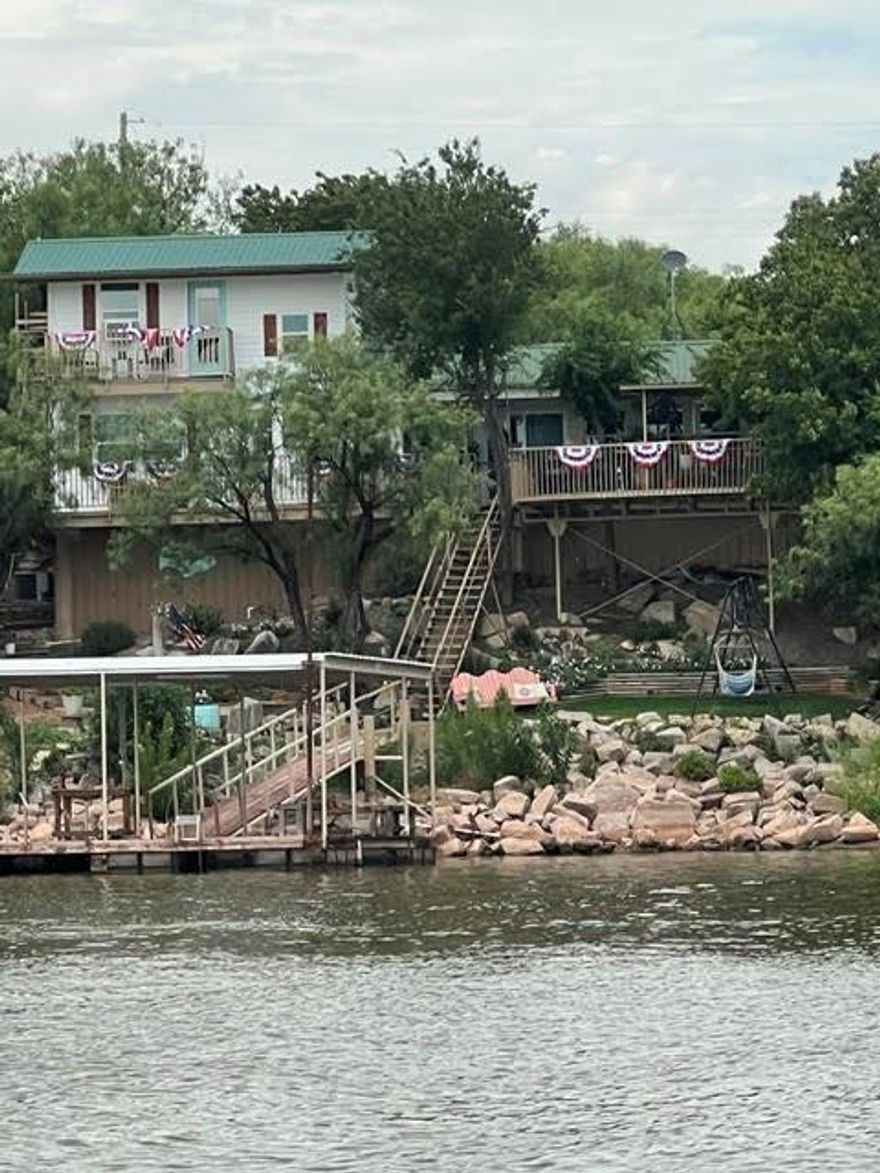 Experience the perfect blend of comfort, style, and lakefront living in this beautifully updated 3-bedroom, 3-bath home offering 1,834 square feet of thoughtfully designed space on a quiet cove with excellent water access, this property offers the ideal lake escape with easy access to public boat ramps located on the next street over. Out for an early morning fishing trip or a sunset cruise, getting on the water couldn’t be easier. A standout feature of this property is the 20’ x 20’ floating boat dock, built in 2019, complete with a boat slip, electricity, and a swim ladder. Lake Fort Phantom is well known for its crappie, bass, and catfish, making this an exceptional spot for anglers. The home has been thoughtfully updated and is truly move-in ready. Recent improvements include new windows, new Hardie Plank siding, and new flooring throughout. The reconfigured kitchen layout enhances both function and flow, featuring a large pantry and an open design that makes cooking and gathering effortless. A spacious laundry room adds additional storage and everyday convenience. On cooler evenings, the Lopi pellet stove is perfect for cozy nights after a full day on the water. Outdoor living is where this property truly shines. Multiple decks and balconies are designed to capture breathtaking lake views from nearly every angle. A spacious covered back deck of over 400 square feet provides the perfect setting. Along the shoreline, you’ll find thoughtfully designed seating areas, including a firepit and a terraced covered patio right at the water’s edge.  A unique bonus space includes an additional bedroom with a separate entrance off the back deck. Situated on a large, beautifully landscaped lot, the property also offers impressive parking and storage options, including a one-car garage, four-car carport, and a storage shed. An insulated workshop provides even more versatility. Don’t miss the opportunity to own this exceptional Lake Fort Phantom lakefront home.