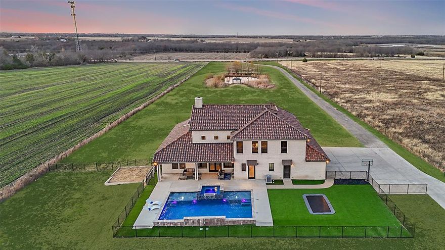 Set behind a private gate on approximately 10 acres in Rockwall ISD, this modern estate offers a rare combination of privacy, scale, and proximity to town. Designed for both everyday living and entertaining, the home features an open layout with vaulted ceilings, expansive windows, and abundant natural light throughout. HIGHLIGHTS: Oversized island kitchen with premium appliances and finishes selected to match the scale of the space—built for real use, not just show. Primary living areas flow seamlessly indoors and out, creating an easy connection to multiple outdoor living spaces. OUTDOOR: A sleek contemporary pool and spa with integrated fire and water elements, an in-ground trampoline, fenced artificial turf yard, and generous patios ideal for quiet evenings or large gatherings. Two ponds enhance the setting and privacy, while extensive concrete provides functional access across the property. This is not a price-per-square-foot offering—it’s lifestyle arbitrage: an opportunity to acquire land, infrastructure, and design that would be cost-prohibitive and time-intensive to recreate today. SHOP + PARKING: New 4,200 SF insulated steel shop with custom roll-up doors, 6-car carport, and additional covered patio space—perfect for storage, hobbies, recreation, or business use. A rare offering for buyers who value space, function, and long-term value in a location that balances privacy with convenience. Ag exempt!