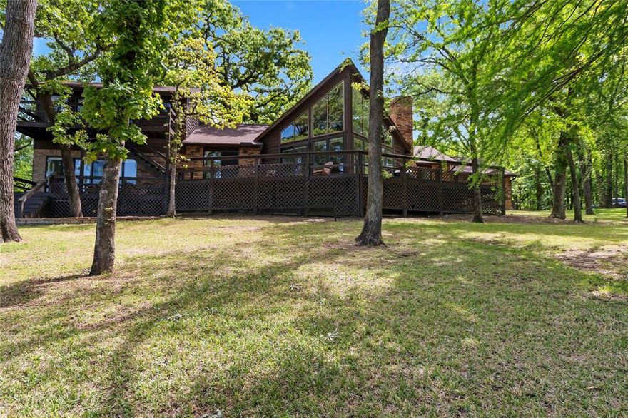 Beautifully updated waterfront home offering approximately 80 feet of shoreline on a .39-acre lot, tucked along a private road for a quiet, tucked-away lakefront getaway. Nestled among mature trees, the property overlooks a wide, protected cove—providing peaceful views along with wind protection ideal for swimming, watersports, and long-term shoreline and boathouse durability. A spacious back deck spans the length of the home, creating an ideal setting for outdoor living and entertaining.

The main living, kitchen, and dining areas have been opened to create a seamless, light-filled space with vaulted ceilings, exposed beams, a wood burning fireplace, and a wall of windows framing the water. The fully remodeled kitchen features a custom island, updated cabinetry with fresh paint and hardware, new countertops, backsplash, sink, faucet, and stainless appliances. The layout includes a private primary suite downstairs, three en suite guest bedrooms on the main level, and an upstairs game room with a half bath—comfortably accommodating a crowd.

Extensive improvements throughout the home include luxury vinyl plank flooring, fresh interior paint, updated lighting with can lights and new ceiling fans, and an electrical system brought up to code. Major system updates include two new HVAC systems installed in 2024, along with a dedicated unit for the upstairs game room.

Outdoor features continue with an approximately $80K composite deck and boathouse completed in October 2025, featuring an 8,500 lb aluminum boat lift for easy lake access. Lake stairs have also been added for convenient access to the water.

Additional features include an attached two-car garage and a second driveway, providing ample parking for guests. Offered mostly furnished, with select exclusions—ready for you to start enjoying the lake right away.
