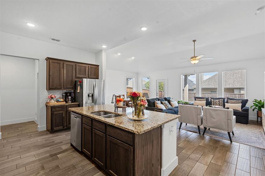 This isn’t your builder-basic box. From the moment you walk in, you’ll notice details that make daily life easier and entertaining more fun, wood-look tile flowing through the main spaces, tall ceilings, and a kitchen that actually feels like the center of the home. The oversized granite island is made for gatherings, while stainless appliances, custom cabinetry, and a sharp backsplash pull the look together. The private primary suite feels like a retreat with its soaking tub, walk-in shower, dual sinks, and big closet. Two more bedrooms sit separately for privacy and flexibility. Smart features like app-controlled lights, thermostat, oven, and a Ring doorbell keep things simple. Out back, a covered patio and sprinkler-fed yard mean low-maintenance weekends. Out front, you’re across from the greenbelt and just steps to the pool, playground, and trails. Add in quick access to Chisholm Trail Parkway, and you’re downtown in minutes.