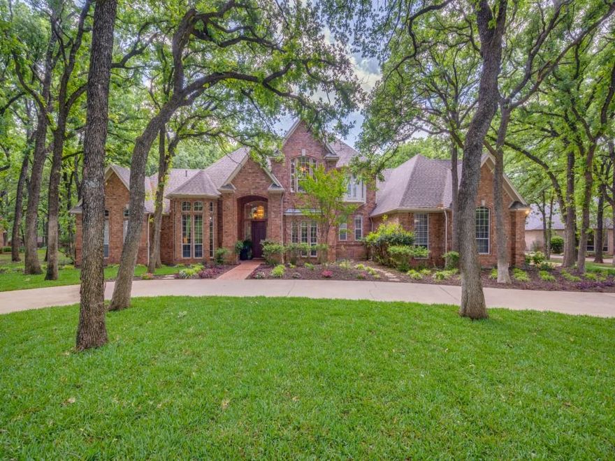 Stunning traditional estate set on over an acre of heavily treed grounds in the exclusive, tucked-away enclave of Brooks Court. This remarkable property offers unmatched privacy & park-like setting, backing directly to Corps of Engineers land and Pilot Knoll Park—delivering breathtaking views, direct access to nature, and a true retreat-style lifestyle. From the moment you enter, you’re greeted by a grand, impressive entry that opens to refined yet inviting living spaces. The living room is a showstopper with custom built-ins, a statement fireplace, and a dramatic wall of windows that flood the space with natural light and showcase the lush surroundings. Designed for effortless entertaining, the dining room flows seamlessly into a wet bar complete with a built-in wine fridge. Hardwood floors carry through to the breakfast and family rooms, which overlook a spectacular backyard oasis featuring a sparkling pool and spa with water feature—your own private resort. The updated kitchen blends style and function with quartz countertops, double ovens, a large island, breakfast bar, and extensive custom cabinetry and storage. A richly paneled study with French doors and built-ins offers a sophisticated work-from-home space.  The primary suite offers a private retreat with an ensuite bath featuring double vanities, a massive walk-in closet, and a cedar closet. A secondary bedroom is conveniently located downstairs. Upstairs, you’ll find two spacious ensuite bedrooms and an expansive game room perfect for entertaining or relaxing. An oversized three-car garage with a built-in workshop adds exceptional functionality and convenience, offering direct access to a spacious laundry room with abundant cabinetry and a sink, as well as a separate entry to a mudroom complete with a built-in desk.  This beautifully maintained custom home is zoned for the highly-desirable Highland Village schools and is conveniently located just of 2499 minutes from excellent shopping and services.
