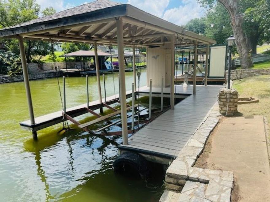 Discover your slice of paradise in this spacious 3-bedroom, 2-bath home located right on the water! Enjoy the luxury of your own private boat dock and lift, ideal for daily lake adventures. With two living areas and a sunroom, this home is built for entertaining—whether you're hosting a sunset dinner or relaxing with morning coffee by the water. Recently updated with fresh paint and new carpet, this home is move-in ready. The newly painted boat dock is perfect for summer fun on the water!  Additional features include irrigation system that pumps from the lake, saves on water bill,  a storage building and extra side parking behind the gates and a community pool and clubhouse .