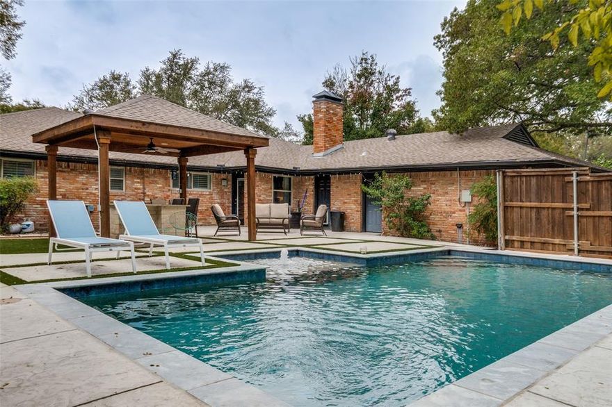 Nestled on a quiet cul-de-sac in Northwest Dallas, this stunningly updated single-story home blends warmth, functionality, and designer style throughout. The open-concept floor plan creates a natural flow between the kitchen, dining, and living areas, making it perfect for everyday living or entertaining. Exposed wood beams, rich hardwood flooring, and a custom stone fireplace anchor the spacious main living room, while oversized windows flood the home with natural light. The kitchen is both beautiful and practical with granite countertops, stainless steel appliances, soft-close cabinetry, and an extended island that provides seating and ample prep space. A built-in desk area and breakfast nook offer versatility for work-from-home or casual dining. The home features four comfortable bedrooms and three updated bathrooms, including a primary suite with a modern en-suite bath that showcases dual vanities, marble counters, and a glass-enclosed shower. Every detail has been thoughtfully chosen, from the lighting fixtures to the hardware, resulting in a cohesive, contemporary feel throughout the home. Step outside to your private backyard oasis complete with a sparkling pool and spa, an outdoor kitchen under a cedar-lined pergola, and multiple lounge areas designed for relaxation or entertaining. Artificial-turf accents and mature trees provide beauty with minimal upkeep. Ideally located near private schools, the Northaven Trail, and major Dallas corridors, this property offers a rare combination of style, convenience, and resort-like living, all in one exceptional package.