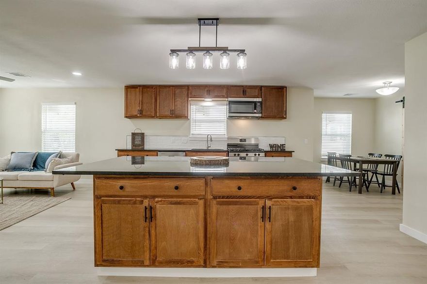 Welcome home to this beautifully updated four bedroom, three bath residence nestled in the established Jones Oakview neighborhood of Haltom City. Thoughtfully designed for modern living, this 1,866 square foot home offers two full primary suites, ideal for large families, multi-generational living, or guests wanting their own private retreat. The interior features luxury vinyl plank flooring and an inviting open concept layout that connects an oversized living area with an expansive kitchen designed for entertaining. The kitchen showcases a massive island, granite countertops, built-in cabinetry, stainless appliances, and abundant prep and storage space, creating a perfect gathering spot for friends and family, especially during the holidays. Each bedroom is generously sized and arranged for both comfort and privacy, with one suite located separately for flexibility. Bathrooms include updated cabinetry, dual vanities, and beautiful finishes that make everyday living feel elevated. Outside, a detached garage provides flexible use for parking, storage, or workshop potential, while the spacious yard invites room to garden, play, or relax. This property offers easy access to downtown Fort Worth, the Stockyards, and the Mid Cities with convenient proximity to major highways, restaurants, and shopping, all within Fort Worth ISD. Combining function, comfort, and a fresh modern style, 1320 Wayne Street is a move-in ready home that perfectly balances everyday convenience with the warmth of thoughtful design.