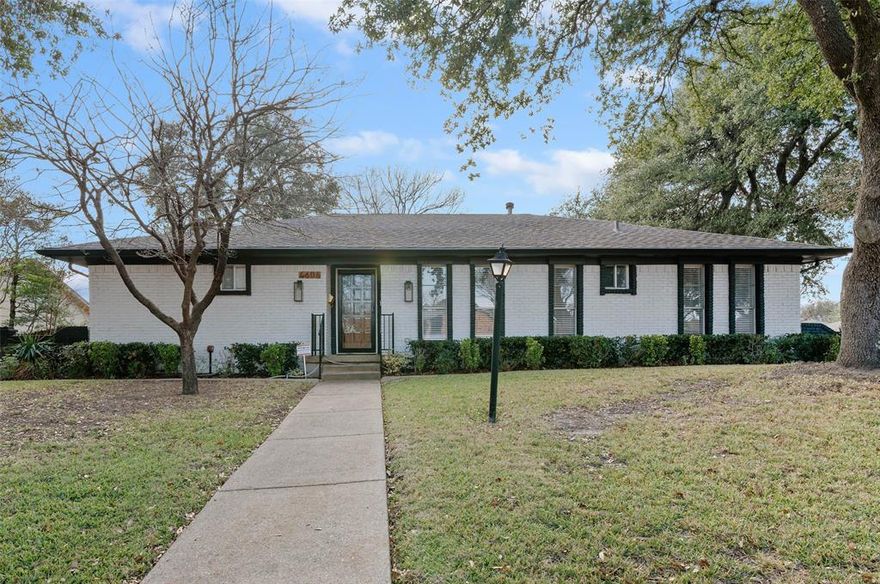 Immaculate and fully renovated, this one-story corner lot home in Buckner Terrace offers 4 spacious bedrooms, 3 beautifully updated full baths, and an attached 2-car garage. From the moment you walk in, the open-concept layout with vaulted ceilings and designer-selected finishes welcomes you in. The chef’s kitchen is a true showstopper, featuring an 8ft x 4ft double waterfall island with Calacatta Sponda Quartz countertops (MSI, 3cm), stainless steel appliances, modern lighting, ample cabinet space, and a stunning designer backsplash. It flows effortlessly into a large living area with an accented brick fireplace, wooden mantel, and wood ceiling beams, perfect for everyday living and entertaining. The flexible dining area opens to the backyard through two separate doors, enhancing indoor-outdoor living. Durable luxury vinyl plank flooring, crisp white walls, and plenty of natural light create a fresh and inviting atmosphere across every room. The primary bedroom offers a walk-in closet w a luxurious en-suite bath with dual vanity sinks, an oversized glass-enclosed shower, and a freestanding acrylic soaking tub surrounded by elegant marble and porcelain tilework. Two additional bedrooms share remodeled full bathrooms, while a fourth bedroom with several windows and a large closet works well as a bright and cheerful office space. Outside, enjoy a fully fenced backyard with a new 8ft privacy wood fence and a covered patio, all set on an almost quarter-acre lot. Upgrades include a 2 year HVAC and duct system, updated plumbing and internal drains, a recently replaced electrical panel and wiring, and full energy-efficiency certification from the city. With no HOA and just 12 minutes from Downtown Dallas, this move-in ready home blends style, function, and location in one beautifully updated package. Hurry! Transferable Home warranty for the buyers with Choice Home warranty through 11.04.2026!