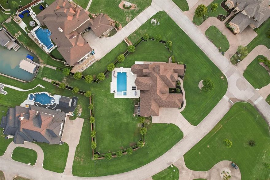 Located in the exclusive, 24-7 gated & guarded golf course community of The Resort on Eagle Mountain Lake, this stunning custom home truly has it all! Boasting 5 spacious bedrooms, 5 full bathrooms, and a half bath, the open-concept layout was designed for effortless entertaining and everyday comfort. The gourmet kitchen is a chef’s dream—complete with a massive island, double ovens, gas cooktop, built-in refrigerator, and walk-in pantry.
The living area features stunning wood beams, stone fireplace with built ins, and opens up to the kitchen making it perfect for entertaining. The main floor features a luxurious primary suite with stunning beams, double doors leading you to your backyard, oversized en-suite bath, and a closet with direct access to the laundry room. Two additional bedrooms on the first floor with en-suite baths, one with exterior access for the ultimate guest suite. A dedicated office, media room, and a large mudroom and laundry area complete the first floor. Upstairs, you’ll find two additional bedrooms with en-suite baths and an additional living area offering privacy and flexibility. Step into your private resort-style backyard with a custom pool and spa, automatic safety cover, built-in BBQ, covered patio with fireplace—and your own boat dock with lift right on the lake. Finally the four garage offers tons of flexibility with one being large enough to fit your boat, jet skis, etc. The community includes an 18 hole golf course, private boat ramp, dock, two pools, fitness center, basketball and tennis court, clubhouse restaurant and bar. Enjoy the elegance, peace, and serenity of Resort styled living while not sacrificing proximity!