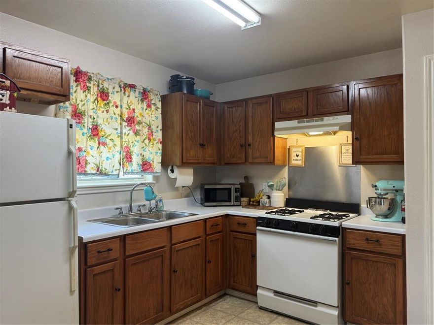 Charming 2-Bedroom Home on Oversized Corner Lot! Welcome to this inviting 2 bedroom, 1 bath home offering 972 sqft of comfortable living space. Situated on an oversized corner lot, this sandstone brick beauty features a spacious fenced yard perfect for your family and pets to enjoy. Mature pecan trees provide shade and character, while a storage  or workshop building adds convenience for all your outdoor needs. Step onto the covered front porch and unwind in the peaceful afternoon breeze. Inside, you'll find an open floor plan that seamlessly connects the kitchen and living room, creating a bright and welcoming space for relaxing or entertaining. Located just two blocks from the school, this home offers unbeatable convenience for families. Whether you're a first-time buyer, downsizing, or looking for a great rental investment, this property checks all the boxes.Don’t miss this opportunity to own a well kept home with plenty of yard space, ideal for gardening, gatherings, or simply enjoying the outdoors. Schedule your showing today!