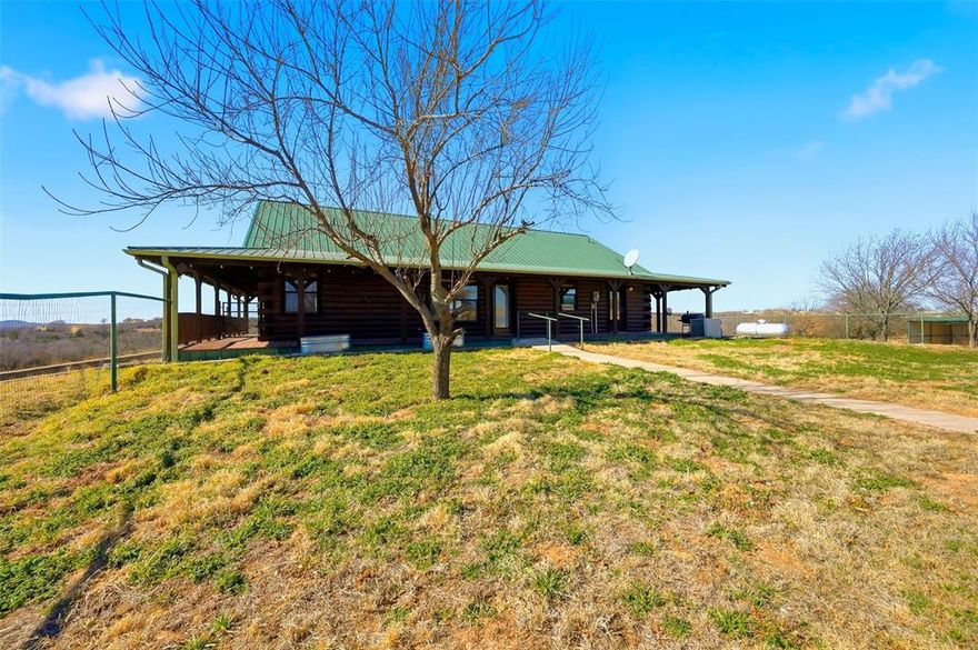 Charming hilltop, ranch style log cabin with full, covered wraparound porch on 7.39 scenic acres in Montague County, with beautiful views of the surrounding countryside, located in Saint Jo ISD. This Ranch Style Cabin features a full wraparound covered porch, 2 bedrooms & 2 full bathrooms on 1st floor with a half bath & 2 flex rooms in the basement that can be used as additional bedrooms, an office, sewing room or game room-man cave. HUGE garage with room for storage & work area. Large kitchen with island that open to the dining and living areas. Property also offers covered parking, septic system, propane and private well. Ideal for those seeking acreage with privacy while still enjoying modern conveniences. Plenty of room for animals, gardening, or future expansion. If you like peace & quiet with gorgeous country views then hurry out here!
