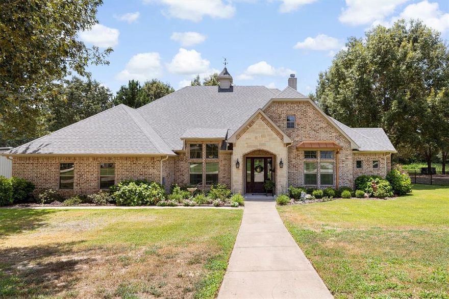 This fully custom, full-brick home sits on just under an acre in a private, no-HOA neighborhood—offering peace, privacy, and convenience. Backing to mature trees and just steps from the golf course cart path, this rare gem is located in the highly rated Lindale ISD. Inside, you’ll find a spacious layout with vaulted ceilings in the oversized living room, a cozy floor-to-ceiling stone fireplace with gas logs, and an open flow into the kitchen, dining area, and large sunroom spanning the entire back of the home. The home runs on well water sourced from an Ozarka spring approximately 100 feet down—providing clean, refreshing water throughout. It also includes two tankless hot water heaters for endless hot water. The oversized garage offers space for a golf cart, extra fridge or freezer, and additional storage. The primary suite is a peaceful retreat with a large bedroom, ensuite bath with a garden tub, walk-in shower, custom closet with built-ins, a laundry chute, and a dedicated safe room. Two more bedrooms share a spacious connecting bath with dual sinks and a large walk-in shower. A generously sized office offers flexibility and could easily serve as a fourth bedroom if needed. Outdoor living shines with a wrap-around extended patio, wooded views, and a huge driveway leading to the 40x60 workshop. The workshop includes electric, three roll-up doors, and attached guest quarters with a private bedroom, full bathroom, living area, and kitchenette. The guest space also features a covered patio overlooking the golf course—perfect for in-laws, guests, or rental income. Located outside city limits, this home offers wide concrete streets, plenty of parking, and a peaceful lifestyle with no city taxes or HOA. Easy access to I-20. Thoughtfully designed and perfectly located, this one has it all.