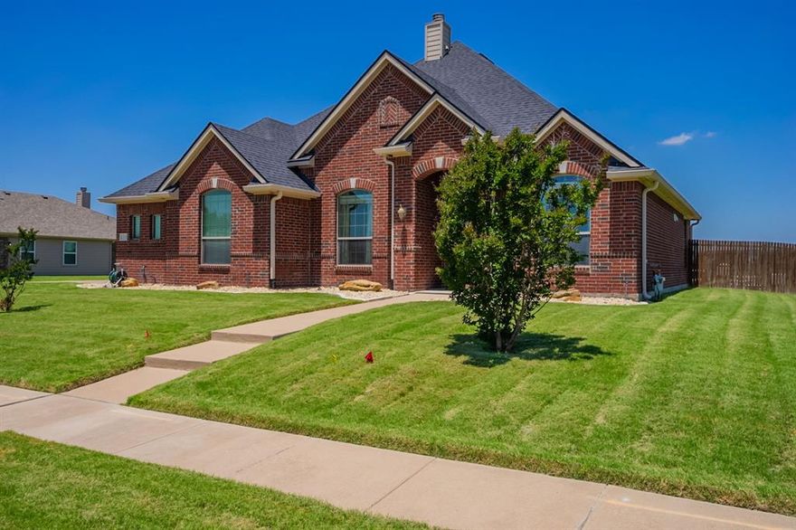 Stunning 3-bedroom, 2-bath Lillian Custom Home loaded with upgrades and designer touches throughout. Highlights include 4-side masonry brick, rich hand-scraped wood flooring, and a dedicated office or flex space. The spacious open-concept living area features a cozy fireplace and flows seamlessly into the island kitchen, complete with built-in appliances, gas cooktop, Sub-Zero refrigerator, granite countertops, and a walk-in pantry. Unique lighting and stylish barn doors add charm and character. The split-bedroom layout offers privacy, while the luxurious primary suite boasts dual vanities, a garden tub, separate shower, and two walk-in closets. Enjoy outdoor entertaining on the extended covered patio overlooking the saltwater play pool and hot tub. Extended driveway adds extra parking convenience.