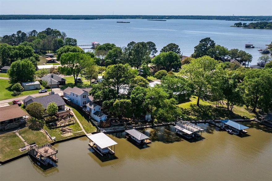 Custom built in 2020, this beautifully designed four-bedroom, three-bath home offers the perfect blend of comfort and lakeside living. The open-concept living and dining area features luxury vinyl flooring, a cozy fireplace, and a dramatic wall of windows that fills the space with natural light and showcases tranquil lake views. The stunning kitchen is equipped with granite countertops, a decorative tile backsplash, stainless appliances, and a spacious island with seating- ideal for gathering with family and friends. The private primary suite is conveniently located on the main level and overlooks the water, offering double vanities and a large walk-in tile shower. Three additional bedrooms and two full baths provide plenty of space for guests. Outdoor living is just as impressive, with lush landscaping, a wonderful covered porch, greenhouse, and a lakeside patio perfect for entertaining. A boathouse with personal watercraft lift makes enjoying the water effortless. The finished summer room offers flexible space for kids, hobbies, or a peaceful retreat. Additional highlights include an oversized two-car garage, extra parking, and even a private pickleball court- creating a true lakeside lifestyle experience.