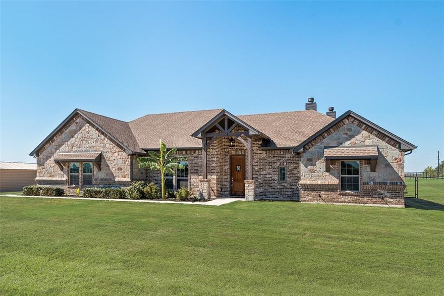Corner Acre Lot • Vaulted Beamed Ceiling • Outdoor Fireplace • Ceramic-Tinted Windows • No HOA
Custom-built 2019 brick home on a 1-acre corner lot in Briar Crossing delivers craftsmanship, comfort, and energy-smart design within minutes of Azle amenities. The single-story 4-bed, 2.5-bath layout spans 2,245 sq ft with an open-concept plan centered on a vaulted great room featuring exposed beams, stained concrete floors, decorative lighting, and a stone wood-burning fireplace. The kitchen pairs granite counters, custom cabinetry, stainless appliances, and a large island for prep and gathering. The private primary suite offers dual vanities, an oversized walk-in shower, and a spacious closet.
Comfort upgrades include ceramic tinting on west-facing windows for temperature control and UV protection, energy-efficient windows, and a smart garage opener. Secondary bedrooms allow flexible use, including a front office option. Exterior enhancements elevate daily living—a powered shed with electric, custom chicken coop, chopped-wood shelter, and a fully pipe-fenced backyard with sprinkler system. A covered patio with an outdoor wood-burning fireplace sets the stage for dining or evening relaxation with Texas sunset views. Durable stained concrete flooring and granite surfaces throughout provide low-maintenance longevity. No HOA and ample space for trailers, boats, or a small RV. High-speed internet available. Close to local coffee shops, groceries, and parks—Texas Drip Coffee (0.7 mi), Pro Liberate Coffee Co (1.3 mi), Briar Hill Grocery (0.7 mi), Albertsons (3.7 mi), Walmart Supercenter (4.5 mi), and Shady Grove Park on Eagle Mountain Lake (3.8 mi). Easy access to TX-199 for commuting to Fort Worth or Weatherford. Modern craftsmanship. Acreage living. Endless Texas charm.