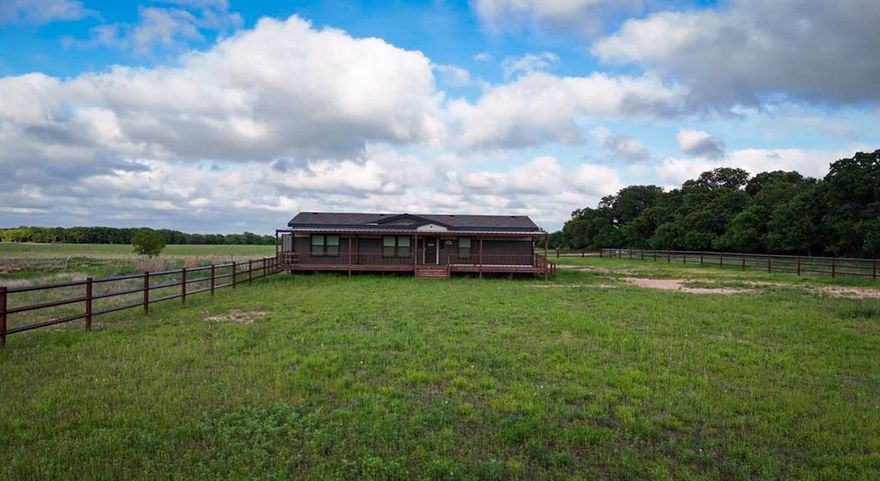 Quiet 20 acre property with county road frontage on two sides featuring a 2024 manufactured home offering 3 bedrooms, 2 bathrooms, and a dedicated media room. Enjoy outdoor living on the 57’ x 16’ covered deck, perfect for watching the sunset.
The property is serviced by a private water well and includes a 24’ x 57’ rear carport with ample covered parking. An 8’ x 4’ storage area located under the carport that is plumbed.Improvements include a 24’ x 75’ open-sided metal barn with a tack room, suitable for equipment, livestock, or future horse use. A 150’ x 250’ arena pad is already in place, making this property well suited for equestrian or agricultural use with room to customize.