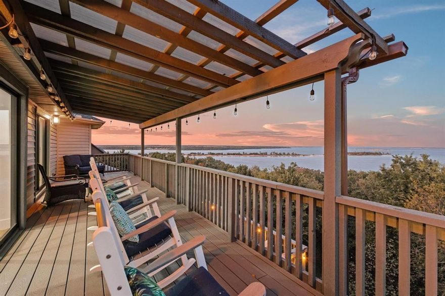We invite you to step inside & fall in love with this stunning waterfront retreat nestled in the highly desirable Russwood subdivision. Perfectly positioned on the upper level of the community, this home offers year-round accessibility —a rare find on Lake Texoma. Just a short walk through the trees leads you to a sandy beach, making this property the ideal blend of convenience & natural beauty. Parking is never a problem here. With an oversized 4-car attached garage and circular driveway, there’s plenty of room for guests—making this home the ultimate entertaining destination. Step inside & be captivated by panoramic lake views through the two-story wall of windows that flood the home with natural light. Facing east, you’ll wake to spectacular sunrises and enjoy a forest-like backdrop that changes beautifully with every season. Best of all, your view will always remain unobstructed—this is true lakefront living, not just lakeview. The main level features an open concept floor plan designed for comfort & connection. The chef’s kitchen offers abundant counter & cabinet space, seamlessly adjoining the great room and dining area for effortless entertaining. Half bath & theater room complete this level. A modern staircase (or private elevator) leads you to the upper level, where a 180-degree sitting room provides one of the best vantage points on the lake—perfect for watching the changing seasons or 4th of July fireworks. The primary suite offers a luxurious ensuite bath & an additional living area, plus another half bath for convenience. The lower level is designed with gatherings in mind—featuring a spacious recreation room, large bath, & 3 bedrooms, including a bunk room that comfortably sleeps nine. Step out to the largest of three decks, perfect for lakeside entertaining, morning coffee, or evening wine with friends. All furnishings negotiable. Don’t wait for summer—start your lake life now & make this magical home your dream waterfront escape for 2026 & beyond.
