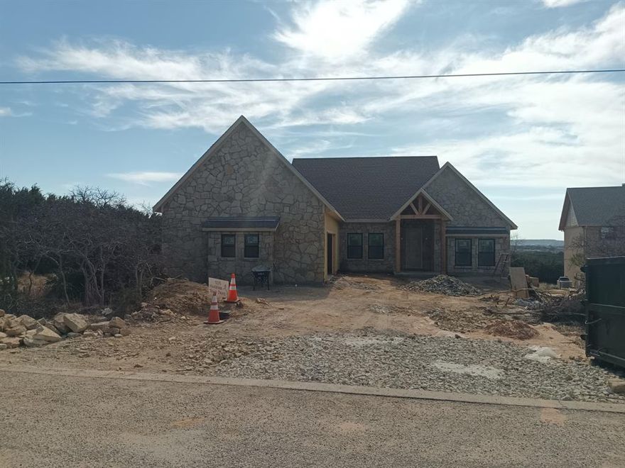 This rustic single story home at 105 Harbour Town Dr is located at The Cliffs Resort in Graford, TX. It is currently being built and will be completed in May of 2026.  It offers 3 bedrooms and 2 full bathrooms, with an open concept and finished area of 1,960 sq.ft. The lot sits high above the cliffs of PK and has an incredible view from the back of the house. All from a single story; no stairs to climb. Located 1 minute from the beach and boat slips. 4 minutes from the restaurant and golf course. Gated entrance and great location. All you have to do is unpack and enjoy.