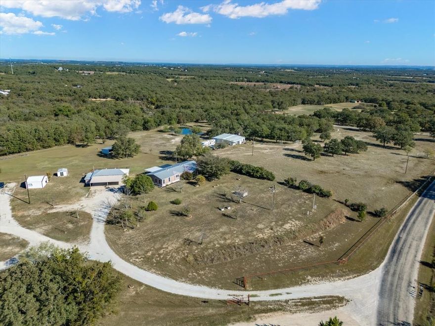Welcome to peaceful country living on 2.37 acres in Paradise, Texas. This fully fenced property with gated entry offers plenty of space to spread out, work, and unwind. The home features four bedrooms and two-and-a-half bathrooms, with both a front living area and a second living space just off the kitchen—ideal for gathering or relaxing. Laminate flooring flows through the main areas for easy maintenance, with carpet in the bedrooms for added comfort. The spacious primary suite is a retreat of its own, complete with a 13x10 sitting room, perfect for a private lounge, office, or nursery. The en-suite bathroom includes a soaking tub, walk-in shower, dual sinks, and a generous walk-in closet. Enjoy quiet mornings and evening sunsets from the covered front and back porches, both offering ample space for outdoor seating and entertaining. Outside, the property continues to impress with multiple functional structures: Detached 3-car garage with an attached carport. Fenced dog run located behind the garage. Loafing shed. Additional storage shed. Workshop with electricity and an AC unit. In-ground storm shelter for peace of mind. Whether you’re looking for room for animals, outdoor hobbies, or simply a little more breathing space, this property delivers. Come enjoy the privacy, versatility, and laid-back charm that Paradise is known for. This one is ready to call home.