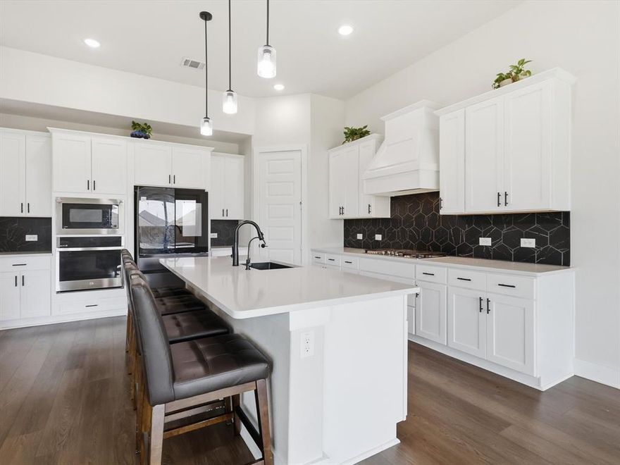 Located in a vibrant Hickory Creek community, this home offers the perfect blend of lifestyle and convenience. Enjoy neighborhood amenities including a community pool, playground, and scenic walking trails, along with exclusive access to Sycamore Bend Park, where you’ll find lake access, camping, and miles of nature trails just minutes away.

Step inside to a light-filled, open-concept design with soaring ceilings and expansive sightlines that immediately make the home feel both spacious and inviting. The heart of the home is the stunning kitchen, featuring a large center island, quartz countertops, stainless steel appliances, a 5 burner gas range, convection oven, and a walk-in pantry. all complemented by sleek, modern finishes, crisp white cabinetry, designer lighting, and a striking backsplash. The space flows seamlessly into the living and dining areas, making it ideal for entertaining.

the first floor includes a spacious primary suite along with a private multi-generational suite complete with its own full bathroom, ideal for guests or extended family.

The primary suite is a true retreat, featuring a bay window, a spa-like bathroom with a soaking tub, dual vanities, and a large walk-in closet that conveniently connects directly to the laundry room.

Upstairs, you’ll find a large game room, dedicated media room, and three additional bedrooms, offering plenty of space for both relaxation and functionality.

Step outside to a covered patio overlooking a generously sized backyard, perfect for entertaining, play, or simply enjoying quiet evenings at home. This home truly combines modern design, thoughtful layout, and an unbeatable lifestyle location, ready to welcome you home.