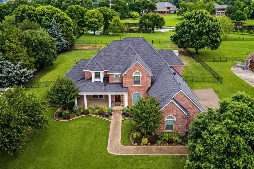 Custom two-story estate on 1.71 acres, ideally positioned on a neighborhood pond, offering serene views and the opportunity for fishing or kayaking. Enjoy the sense of arrival each day, driving home to a peaceful setting surrounded by nature and open space. A welcoming extended front porch sets the tone for this thoughtfully designed home, ideal for both entertaining and everyday living. Inside, a grand sweeping staircase anchors the space, complemented by classic millwork, real hardwood flooring, extensive built-ins, and formal living and dining areas. Six 6' x 10' picture windows showcase outdoor views in family & breakfast areas. The spacious kitchen features abundant cabinetry and prep space, a built-in refrigerator, gas cooktop, and Thermador Professional Series double ovens (Dec 2023). A generous Butler’s Pantry enhances storage and service, while a wet bar with icemaker & beverage refrigerator supports effortless hosting. A private study with coffered ceilings, French doors, and built-ins provides an ideal work-from-home setting. The downstairs Primary Suite offers a well-appointed ensuite bath, walk-in closet, jetted tub, updated lighting, and custom linen storage. Also, find recently replaced carpet downstairs, neutral paint tones, LED lighting, plantation shutters, double-pane windows (installed 2010), as well as elegant arched doorways and crown molding throughout. Upstairs includes four spacious bedrooms with remodeled Jack-and-Jill baths and a large game room with vaulted ceilings. The backyard is a true highlight, featuring an extended covered patio, built-in grill, expansive lawn for recreation, and a beautifully designed garden—all overlooking the tranquil pond. Additional features include three Lennox HVAC systems (2020 & 2021), two 50-gallon high-efficiency water heaters (2021), a 26KW whole-house generator (2023), Class 4 roof (2016), oversized three-car garage with Racedeck flooring, and excellent storage throughout. Plano ISD & low Parker taxes.