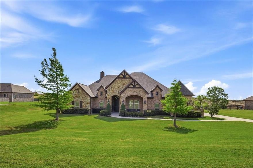 Set on a full acre in the gated enclave of Lago Vista at Bonds Ranch, near Eagle Mountain Lake, this impeccably maintained Ashland Homes residence blends privacy, scale, and thoughtful design in one of Fort Worth’s most sought-after pockets.

Built in 2015 the property sits on a a little over an acre with views, creating a rare sense of space and seclusion. Inside, architectural details immediately stand out—graceful archways, cased windows with shutters, wood beams, and a striking stone fireplace anchor the main living area, while natural light flows effortlessly throughout.

The heart of the home is a true entertainer’s kitchen, centered around an impressive 10x6 island with abundant storage. Outfitted with stainless steel appliances, a over-sized walk-in pantry, butler’s pantry with wine bar, and a charming breakfast nook, it seamlessly connects to both the formal dining room with raised ceiling and the inviting living space.

A smart, split-bedroom layout offers both functionality and privacy. Two secondary bedrooms share a Jack-and-Jill bath with granite finishes, framed mirrors, and built-ins, while a separate playroom anchors the secondary wing. A dedicated office with glass doors and closet provides flexibility for work, additional living or bedroom.

The private primary suite is a true retreat, featuring a coffered ceiling, brand-new carpet (2026), and a spa-like bath complete with separate vanities—including a seated vanity—dual showers, whirlpool tub, and an expansive walk-in closet with floor-to-ceiling storage. Direct access to the laundry room adds everyday convenience and privacy.