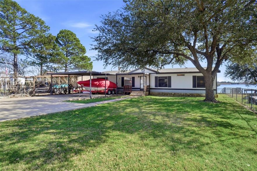 Fantastically Maintained LAKEFRONT on Lake Granbury. Make memories that last a lifetime! This 3-bedroom, 2 bathroom retreat, perfectly positioned directly on the MAIN BODY of Lake Granbury. If you're looking for big water views and deep water access, this is the one! The interior is designed for both relaxation and entertaining, featuring two living areas that provide ample space for guests to spread out. A cozy wood burning fireplace offers the perfect focal point for chilly evenings after a day on the water. The eat in kitchen complete with space for a table & breakfast bar seating, & flows seamlessly into the two main living spaces, making morning coffee with a view a true luxury. Ensuite owners retreat and good size secondary bedrooms for room to spread out and have guests stay! The outdoor amenities truly set this property apart. Step out onto the spacious covered deck, an ideal vantage point for shaded afternoons, sunset evenings or late night stargazing over the open water. This home is fully fenced offering a secure environment for pets or play. Convenient storage shed for all your lake gear and fishing tackle. Parking is a breeze with the gated double carport, providing protection for our vehicles and toys. Water enthusiasts will fall in love with the private dock which was added in 2022 & 23 and ready for you to add your canopy and lift. Just out your back door is immediate access to boating, wakeboarding, fishing, floating, and sunset cruises.  Nestled in a wonderful established neighborhood you'll enjoy the peace of a private oasis alongside fantastic community amenities.   Whether looking for a full time residence or a weekend getaway, this home offers the perfect setting to make great memories on the Lake. Don't miss your chance to own a piece of Lake Granbury's most sought after shoreline! Boat and home furnishings are negotiable. See Remarks
Home is Certified Manufactured home. Please see Offer Guidelines in Transaction Desk.