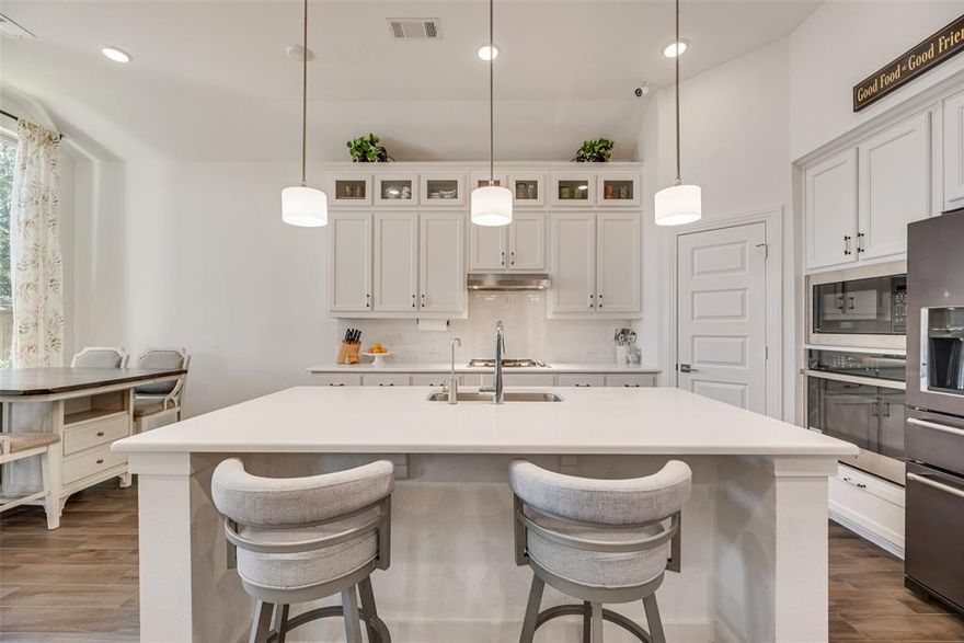 Welcome to resort-style living in the Inspiration Neighborhood at its finest! This One-Story meticulously maintained Highland Home with highly Desirable Dorchester Floor Plan is a RARE and a GEM. Inside, you’ll be greeted by an immediate view that carries through the archways, and 12’ ceilings, past the inviting floor-to-ceiling stone fireplace to your massive outdoor patio  oasis. The home features wood-like tiles for easy maintenance, a custom built-in coffee, wine and beverage bar that makes entertaining effortless, while the sitting area provides a flexible space—perfect as a second dining room, reading nook, or conversation lounge. A spacious office with French doors offers privacy for work or study. The current exercise room can also be easily drywalled and converted into an additional bedroom. The open-concept kitchen features stainless steel appliances, a large island, quartz countertops, and abundant cabinetry, all open to the main living spaces for seamless flow. The private primary suite features a primary bath with dual vanities, dual shower heads including a rain shower head, and a vanity space for makeup. Step outside to your own private backyard oasis! The expansive covered patio with stamped concrete sets the stage for year-round entertaining and relaxation. Fire up the built-in grill for weekend cookouts, unwind in the hot tub after a long day, or simply enjoy the serene setting. Hot Tub stays along with the motorized white screen projector by the spa and Govee Outdoor Lights. Security cameras and TV stays and all TV mounts and wall shelves. This community has 27 parks, playgrounds, dog parks, greenbelts, resort-style pools, pickleball courts, and a two-story fitness center with Lake Lavon views at Club Inspiration. Residents also enjoy a private event space, scenic horseback riding along the Trinity Trail, plus boating, fishing, and paddle boarding just steps away.