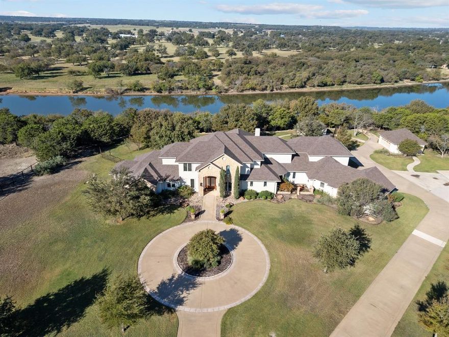 This is a rare opportunity to own this stunning two-story home spans an impressive 7,410 square feet on a sprawling 4.4-acre lot, nestled alongside the beautiful Brazos River. With breathtaking sunsets over the water, this property offers the perfect blend of luxury and tranquility Texas style. Step inside to discover a thoughtfully designed layout ideal for both relaxation and entertaining. The main floor features spacious living areas, including a theater room for movie nights, a game room for friendly competitions, and an inviting office space for work or study. The gourmet kitchen is equipped with a reverse osmosis system, ensuring fresh, purified water at your fingertips, while a second kitchen provides added convenience for entertaining. Venture outside to your own private oasis. Enjoy sunny days lounging by the sparkling pool or unwinding in the hot tub, surrounded by lush landscaping and serene views. The outdoor built-in grill is perfect for hosting summer barbecues, while the expansive patio allows for seamless indoor-outdoor living. For water enthusiasts, the property boasts a private covered dock with sun deck complete with a boat and jet ski lift, providing direct access to the Brazos River for endless adventures. Community boat ramp also available. The second detached two-car garage offers additional storage and space. With ample room for family and friends, this home is designed for unforgettable gatherings. Whether you’re hosting a lively get-together or simply enjoying a quiet evening watching the sunset, this property is truly a slice of paradise.  Don’t miss the opportunity to make this riverfront haven your own! Check out Taylor Sheridan’s Bosque Ranch located in the Silverado development. You can make this a turn key move-in ready deal as the seller would like to sell separately all art, decorations and furnishings. Great vacation home or primary residence. Adjoining 2.16 acre lot also available for sell.