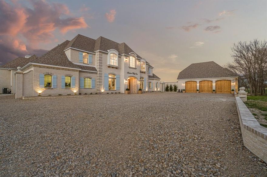 Tucked behind beautiful private gates and a canopy of towering trees on 10 pristine acres in Aledo, this extraordinary French Country estate offers a rare blend of privacy, craftsmanship, and thoughtful design just five minutes from Press Café and I-20. A grand entry foyer welcomes you with light checkered tile flooring, soaring ceilings, flanked by a formal dining room and designated study. Beyond the foyer, the home opens into the heart of the living spaces where dramatic cathedral ceilings in the living room and kitchen create an incredible sense of scale and light. The chef’s kitchen, accented with warm brick and stone, features a massive island, butler’s pantry, and herringbone wood floors that continue into the living area. Picturesque windows throughout fill the home with natural light and frame views of the surrounding acreage. The living room is anchored by a grand floor-to-ceiling stone fireplace, flanked by built-ins with brick accents. One of the home’s most unforgettable spaces is the grand bibliothèque an extraordinary library featuring dual fireplaces, custom built-ins, a full bar with ice machine and refrigerator, creating the perfect setting for entertaining or quiet evenings. Entertainment continues with a first-floor theater room. The primary suite, features paneling, rich hardwood floors, a fireplace, while the spa-inspired bath showcases polished neutral checkered flooring, a walk-through brick shower, and a freestanding soaking tub. Separate his-and-her closets provide exceptional storage. A laundry within the primary closet adds everyday convenience. Built with exceptional efficiency, the home is fully encapsulated with spray foam insulation for year-round comfort. Additional highlights include a five-car garage, spacious guest suites, and a thoughtfully designed floor plan with no wasted space. A survey, pool renderings, and build plans are available upon request. Select furnishings are available to purchase upon request.