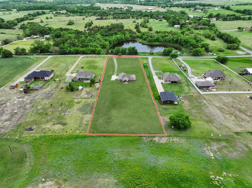 Set on a picturesque 1.88-acre homesite in Howe  TX.  This beautifully maintained ONE STORY home offers the perfect balance of space, comfort, and high end finishes.  AT 1556 square feet  for those buyers seeking room to breathe without the upkeep of a large property, this is that rare “just right” acreage keep reading.  Enjoy peaceful views of a charming pond and plenty of rear outside space to make your own.  Inside, the home feels like new with rich wood flooring, a light and inviting layout, and true move-in-ready condition. The thoughtfully designed single-story floor plan is ideal for those looking to downsize without compromise, offering easy living and seamless flow. The kitchen is a standout with elegant cabinetry, upgraded appliances, a gas cooktop, pantry, refrigerator and a huge  island with bar seating. Step outside to a spacious covered back patio—with no neighbors on top of you there is privacy, perfect for relaxing evenings, entertaining guests, or simply taking in the tranquil setting.  Get that smoker out for year round use. The primary bedroom is a WOW.  High ceilings, walk in closet, and an amazing Gotta See shower for this size square foot home. Pebbled floor and stone with frameless glass. The double vanities and upgraded cabinets tie in the space with elegance. The 2 ancillary bedrooms are split from the primary allowing a wing for the primary and a wing for the other 2 bedrms.  If you’ve been searching for a one story property with manageable acreage and a touch of country charm, this is a property to check out. Howe is an awesome community about 12 miles from Sherman and 25 miles from McKinney. Oh make sure to tour at dusk to catch the beautiful sunsets. Get the country life without sacrificing city amenities.  Refrigerator and washer dryer included.