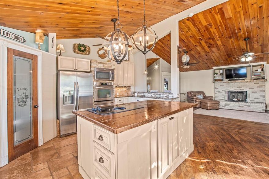 Enjoy water views from both the front and back of this delightful lakefront property, featuring a beautifully updated 2BR 2BA main home and a charming 2BR 1BA guest house. The main home offers 1,658 sq ft of thoughtfully designed space. Most of the home taken to the studs in 2011, it now showcases hand scraped wood floors, a vaulted pine ceiling, and a cozy wood-burning fireplace in the living room. The kitchen is ideal for entertaining, with travertine tile floors, a farmhouse sink, island, walk-in pantry, and double ovens. Remodeled bath features a Jacuzzi tub. The 652 sq ft guest house includes two bedrooms, a full bath, and a light-filled living room with soaring ceilings. The dining and kitchen area has a refrigerator and bar space plumbed for a sink. Upstairs, a fun sleeping loft accommodates seven with one full bed and three twin beds, plus an additional room with two twin beds perfect for guests or vacation rental flexibility. A spacious courtyard patio connects both homes, and each has its own generous covered deck. The flagstone patio below leads to a fully equipped outdoor kitchen with grill, sink, Green Egg, and warming drawer ideal for lakeside gatherings. After a day on the water, soak in the 8 person hot tub. Ample storage under both homes is perfect for water toys and lawn equipment, and a circular driveway offers plenty of parking. The 2020 built boathouse accommodates a boat and two personal watercraft. Located just around the corner from Lone Star Marina and the popular Tiki Hut Restaurant. Home is offered mostly furnished with a few exclusions making this a turnkey opportunity to enjoy lake living immediately. Watercraft available separately. A fantastic primary home, vacation escape, or could be income producing short-term rental. See agent remarks for exclusions.