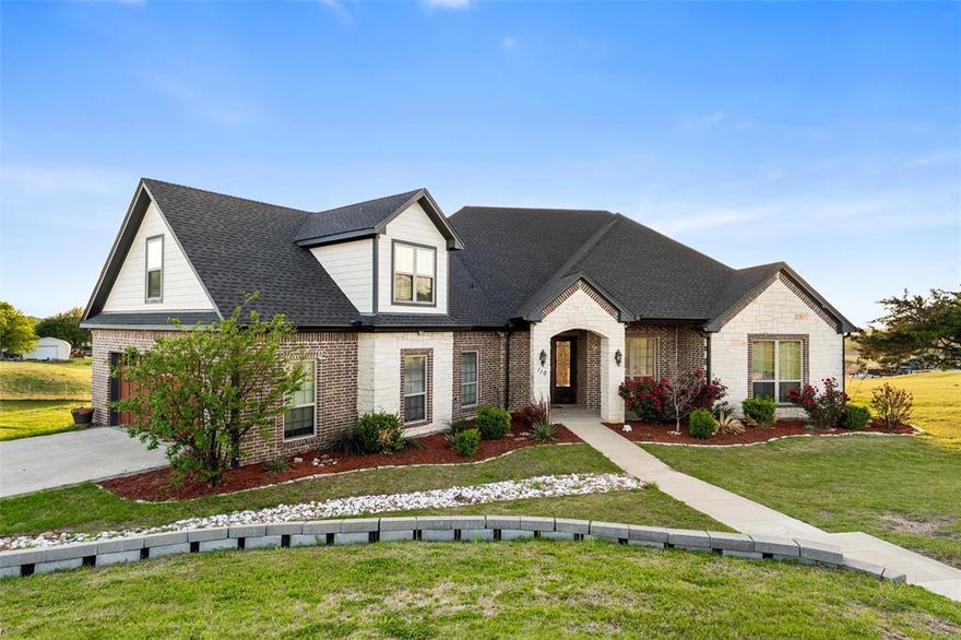 Set on a beautifully elevated homesite with sweeping views of open pasture and a peaceful pond, this thoughtfully designed home blends timeless finishes with a layout that truly lives well. Inside, rich hardwood flooring runs throughout the main living spaces, complemented by detailed crown molding, abundant natural light, and a stunning stone fireplace flanked by custom built-ins. The open-concept design connects seamlessly to the kitchen, where a large island with contrasting cabinetry, granite countertops, farmhouse sink, stainless appliances, and extensive storage make it both functional and visually striking—perfect for everyday living or hosting.

The primary suite offers a true retreat, featuring a spa-inspired bathroom with a freestanding soaking tub, oversized walk-in shower, dual vanities, and a spacious walk-in closet with built-ins. Secondary bedrooms are generously sized with continued hardwood flooring and great natural light, while the oversized utility room is both practical and polished with ample cabinetry, folding space, and room to stay organized. Upstairs, a large bonus room provides flexible space for a media room, game room, or additional living area.

Outdoors, the covered back patio is a standout feature, finished with a warm wood ceiling, recessed lighting, and plenty of room to relax while taking in the expansive Texas views. The setting offers a rare combination of privacy and scenery, backing to wide-open land rather than neighboring homes. Additional highlights include propane gas servicing the fireplace, cooktop, and water heater, enhancing both efficiency and performance. This is a home that delivers space, comfort, and a setting that’s hard to find.