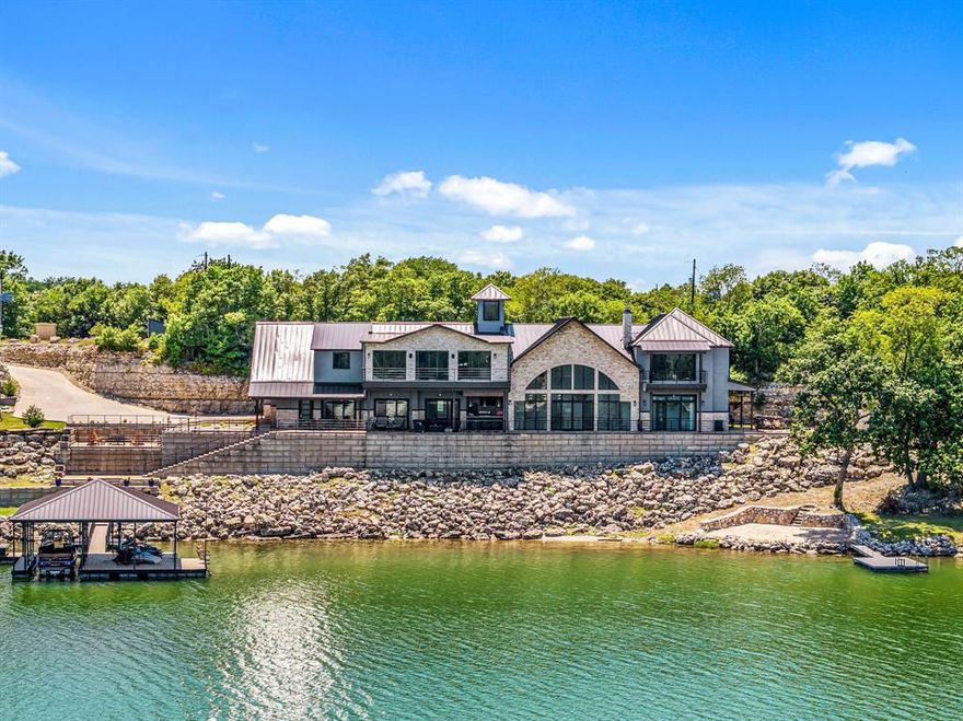 Truly unparalleled, private state-of-the-art lakefront estate situated on 1 acre with nearly 400 feet of pristine waterfront on beautiful Moss Lake. Designed for exceptional indoor and outdoor living, the home captures panoramic lake views from nearly every space and feature and expansive open-concept design with soaring ceilings and walls of glass! The gourmet kitchen is a true showpiece with top-of-the-line appliances, heated floors, a stunning all glass wine room and a hidden oversized pantry that also serves as a secure safe room. The primary suite is privately located on the main level with direct access to an outdoor patio complete with a fireplace and easy access to the beach area. The spa like primary bath features heated floors, a steam shower, coffee bar and custom cabinetry. A private staircase from the primary bedroom leads to a bonus living area with balcony overlooking the lake and a dedicated exercise room. Three spacious guest suites on the lower level each include private terrace access through sliding glass doors, their own bathroom and individual thermostats for ultimate comfort. Upstairs offers incredible entertaining space with a lakefront game room and private balcony, a fully equipped theatre room, and an impressive bunk room with eight queen beds and a loft, perfect for hosting large gatherings. The oversized heated floor garage provides ample room for multiple vehicles, boats and recreational toys. Outdoors, enjoy direct lake access with a Wahoo boat dock, expansive terraces and breathtaking waterfront scenery. Meticulously built by the seller himself with no expense spared, this extraordinary property offers craftmanship, luxury and amenities rarely found in one home. Truly a one-of-a-kind exquisite North Texas retreat with far too many features to list!