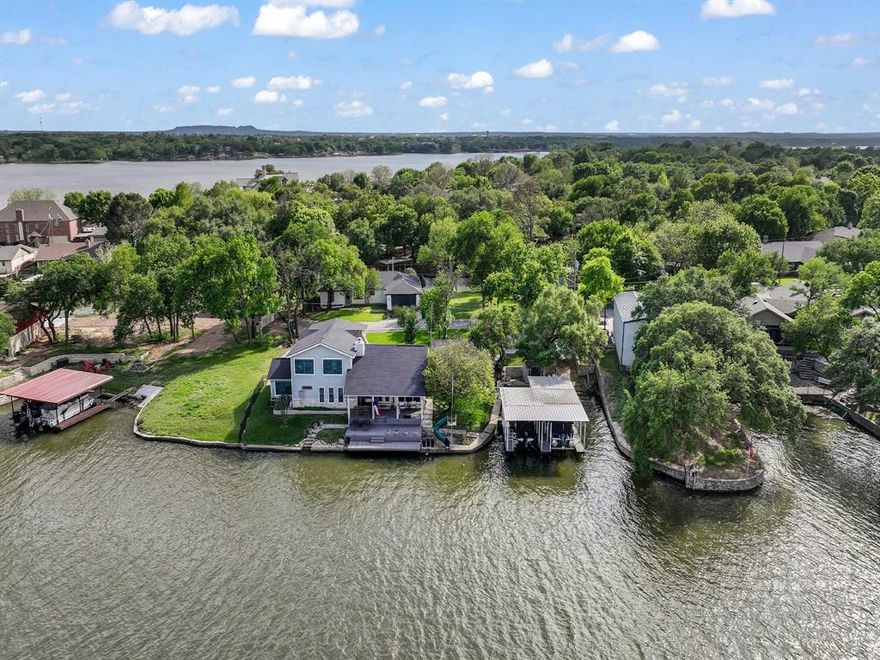 Peaceful waterfront retreat at Bee Creek on Lake Granbury, set on two lots with 150 feet of waterfront, stunning water views from all bedrooms and the living area, and plenty of space between neighbors for added privacy. This 3-bedroom, 3-bath property offers a spacious outdoor living area, fire pit, private boat ramp, two-stall boat dock, room for two jet skis, a triple deck off the back porch for easy access to the water, and a swing off the boat dock. The kitchen features a commercial refrigerator and freezer. The separate mother-in-law quarters include a bedroom, bathroom, and kitchenette. This is a rare opportunity to enjoy waterfront living with space, privacy, and exceptional views.