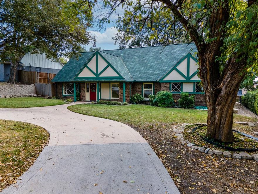 Those who appreciate character-rich homes will love this blend of storybook charm & modern comfort at an affordable price! This Tudor-inspired home with many updates is conveniently located in established, tree-lined, central Rockwall just blocks from Lake Ray Hubbard & served by the renowned Rockwall ISD. There is easy access throughout the DFW area via I-30, Hwy 205 or Hwy 66. The home boasts classic architectural features with its steeply pitched gable roof, decorative half-timbering, & diamond lattice front windows. A welcoming covered front porch is flanked by mature trees & landscaping plus a large circle drive allowing off-street parking for three vehicles. A lengthy back driveway & two car garage provide private parking for several more vehicles. The home's distinctive vibe is accentuated by a custom roof with 50 year shingles & matching trim. Inside features a striking brick fireplace in the main living area & updated vinyl plank floors throughout. The large primary suite is on the main floor, adjacent to a second living area perfect for an office or game room. Upstairs, three large bedrooms are served by a hall bath with double sinks ready for your cosmetic updates. The kitchen & laundry room were remodeled in 2022 with custom cabinetry, storage galore, tile floors, fresh lighting, & granite counters. It features double SS ovens & a 2025 microwave. The primary ensuite bath was updated in 2021 with a walk-in shower, granite counters &  bidet & is cleverly designed with a pocket door separating the main ensuite from a dual purpose powder bath. Swing open the french doors, step onto the huge back patio & relax in your peaceful, shaded back yard oasis. Home was pre-inspected & repairs made for the buyer's peace of mind, including clean roofing, engineering & HVAC reports. 2019 water heater, 2025 gas line & meter, 2023 fence, 2023 east retaining wall, 2025 elect & plumb upgrades. All dates are approximate. No HOA or MUD. Cash, Conv, VA, FHA offers welcome!