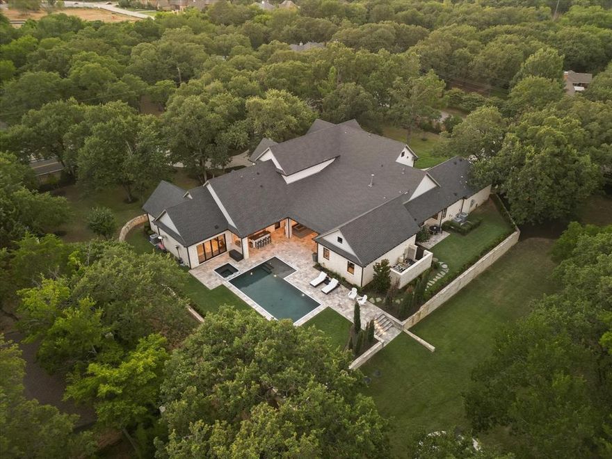 This Austin stone private estate is situated on a 1.3± AC corner lot surrounded by lush trees & complete w a fully fenced yard & 3 gated drives. As you walk through the front door, be greeted by the grandeur of the beamed cathedral ceilings in the great room, seamlessly connecting to the kitchen, pool & patio. Chef's kitchen features Aria quartzite, Wolf appliances, Subzero fridge-freezer & 2 sinks. Four sets of accordion doors provide open access to all outdoor living. The zero-edge pool & spa are the crown jewel of the backyard, complemented by the outdoor kitchen & fire pit. Primary suite opens directly onto the pool deck & features a spa-like bath w his-and-her vanities, custom closets, garden tub & oversized shower PLUS an additional washer & dryer. All secondary bedrooms (1 down, 3 up) offer ensuite baths & large closets. The gameroom is perfect for entertaining offering oversized bar & direct access to the pool deck. Savant home automation, video surveillance & sound system.