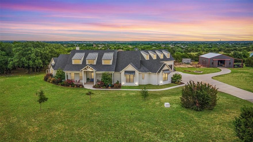 This stunning home in Aledo ISD blends Modern Farmhouse luxury & rural living in this remarkable 12.48-acre property. Sitting proudly with a glorious view, this 5-bedroom, 6.1-bath home features a sprawling open floorplan with 4 ensuite bedrooms & separate guest quarters.The thoughtful design & high-end features include a chef's kitchen with two islands,three ovens, 48in GE 6 burner & loads of cabinets. Spectacular white oak floors, encased wood beams, custom lighting,3.5-inch plantation shutters throughout.Charming library or office with barn door & built-in shelving is perfectly tucked away for privacy.Huge near floor-ceiling Pella windows open gracefully into the outdoor kitchen, living, & sparkling pool area.The large Primary Bed with access to the pool area also offers a sitting area, gracious bath with separate vanities & expansive closet. Guest quarters on 2nd floor has separate outdoor entry.Barn with 3 stalls,tack room,& storage loft;chicken coop.Lots of room for your animals!