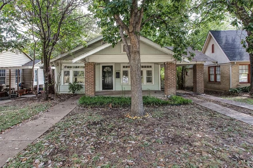 Discover your opportunity to own this charming Hillcrest bungalow perfectly located just off the historic bricks of Camp Bowie. Surrounded by tree-lined streets and timeless architecture, this home places you minutes from Rivercrest Country Club, the Cultural District, and vibrant downtown Fort Worth, an unbeatable combination of neighborhood tranquility and city convenience.  A welcoming covered front porch sets the tone for the warmth inside. Gleaming hardwood floors flow through the majority of the home, while built-ins frame the cozy living room fireplace. The spacious dining room with French doors opens to the kitchen, featuring a gas stainless-steel range. The primary suite is ensuite, and the flexible layout offers multiple room use options. The second full bath highlights a classic claw-foot tub.  Additional features include a separate utility room, basement access from the backyard, an attached brick porte cochere, and a large backyard with alley access. Enjoy living in one of Fort Worth’s most desirable and walkable neighborhoods, moments from fine dining, boutique shopping, and the city’s best cultural venues.