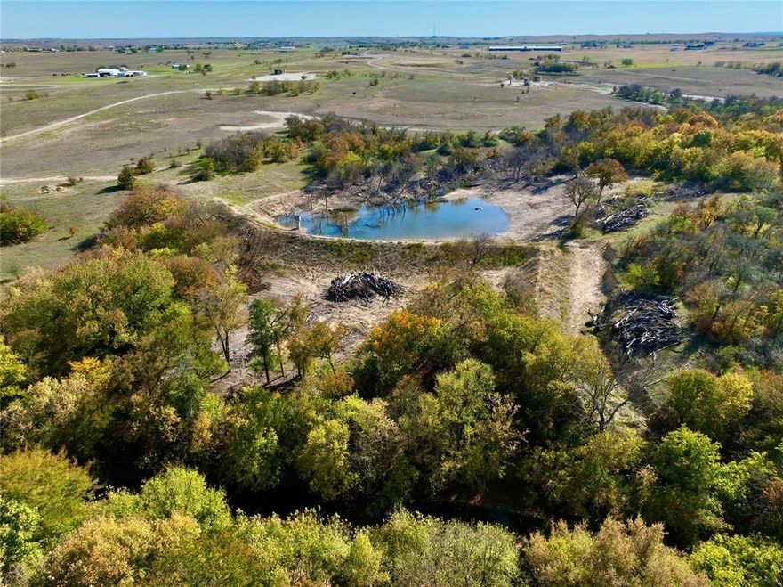 Conveniently located less than 30 minutes north of Ft Worth and less than 1 mile off US 287 lies this 80-acres of undeveloped land featuring Oliver Creek along the north boundary. A wide flagpole like entrance down a recently installed road provides a private gated entrance with easy all-weather access to the bulk of the property set back away from the county road in a peaceful and private location. Falling in elevation from the south to the north, there are great views overlooking the city of Decatur. There is a nice pond stocked with quality fish and beautiful trees along the creek. With the high diversity of trees and a couple of water sources, an outdoor enthusiast can enjoy a plethora of wildlife including ducks, dove, feral pigs, and white-tailed deer. With scenic overlooks of Oliver Creek and the large pond at the back of the property, someone has the opportunity to buy this property to build their dream home with views or use the large acreage as a recreational get away being so close to town. There is only 1 oil and gas location on the property that is in production. Outside of the city limits and ag exempt, a water well and septic system would be needed for a residence.