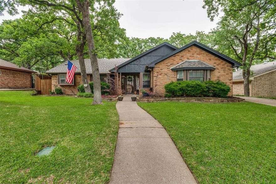 Tucked beneath a canopy of mature trees, this Hurst home offers the kind of space, updates, and layout that simply makes everyday living feel easier. Inside, the spacious living room easily accommodates larger furniture and gatherings, all anchored by a beautiful brick fireplace and a striking wood-beamed vaulted ceiling. The kitchen is filled with natural light thanks to a large front-facing window, creating a bright and welcoming space to start your mornings. Butcher block countertops, ample storage, and a functional layout make it as practical as it is inviting. One of the standout features is the flexibility of the primary suite. In addition to the bedroom, there’s extra space that could easily serve as a home office, nursery, sitting area, or additional storage—whatever fits your season of life. A charming bay window adds even more character and functionality. Both secondary bedrooms are well-sized and offer oversized closets, giving you the storage space that’s often hard to find.

Step outside and you’ll see where this home really shines. The oversized backyard is framed by mature trees that provide incredible shade during the Texas summers. A large concrete patio with a built-in cover creates the perfect space to relax, entertain, or simply enjoy watching kids or pets play. The rear-entry garage, tucked behind an electric gate, adds an extra layer of privacy and security. This is a home that blends thoughtful updates with flexible living spaces and a backyard designed to be enjoyed year-round—all in an established neighborhood within the highly desired Birdville ISD!