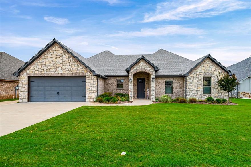 Beautifully maintained 4-bedroom, 2-bath home in the newest area of Pecan Plantation with exceptional curb appeal and thoughtful upgrades throughout. Upgraded stone and brick exterior, mature landscaping, and a peaceful lot create a warm and inviting first impression. Spacious open floorplan features a large living room with fireplace and a bright open kitchen with granite countertops, custom cabinetry, abundant storage, breakfast bar seating, and new stainless steel appliances. Refrigerator, washer, and dryer all convey, making this home truly move-in ready. Designer colors and ceiling fans throughout add warmth and comfort. Home also features hardwired internet connections throughout with centralized network wiring and a OneHome smart home system for seamless connectivity and modern convenience. Covered back porch overlooks the landscaped backyard and offers the perfect space to relax or entertain. Oversized 2-car garage includes EV wiring, side entry door, built-in storage racks, plus additional golf cart garage or storage area with separate driveway access. Conveniently located near the front gate for easy access to Historic Granbury Square, shopping, dining, golf, and community amenities. A must-see home loaded with upgrades buyers will love.