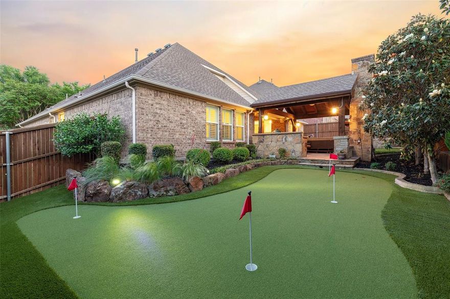 Located in the highly sought-after master-planned community of Cambridge in McKinney, 613 Fortinbras Drive offers the layout, upgrades, and lifestyle you want. This thoughtfully designed 1.5 story home combines functional everyday living with elevated indoor-outdoor entertaining, creating a property that stands out. The flexible floor plan includes 3 bedrooms, 3.5 bathrooms, and a dedicated office created from the original fourth bedroom, offering an ideal setup for remote work, studying, or multi-purpose living. The upstairs has a spacious game room or secondary living area, creating separation from the main living spaces and providing the versatility buyers want for media, fitness, hobbies, or guest overflow. Inside, rich hardwood flooring, soaring ceilings, and natural light create a warm, inviting atmosphere throughout the home. The open-concept kitchen anchors the main living area with custom cabinetry, granite countertops, stainless steel appliances, gas cooking, expansive prep space, and a large island designed for gathering and entertaining. The adjacent dining and family room flow seamlessly together, centered around a striking stone fireplace that adds warmth and character. The private primary suite offers a quiet retreat with a sitting area, plantation shutters, a spa-inspired bath with a soaking tub, an oversized walk-in shower, dual vanities, and generous storage. What truly sets this property apart is the backyard experience. Designed for year-round enjoyment, the outdoor living area features an extended covered patio, an outdoor kitchen, a vaulted wood-beam ceiling, a fireplace, a hot tub, and a professionally designed putting green surrounded by mature landscaping. It delivers the type of resort-style outdoor living you have always dreamed of. Positioned near top rated McKinney ISD schools, shopping, dining, parks, golf, and major commuter routes, this home offers the combination of lifestyle, functionality, and entertaining space.