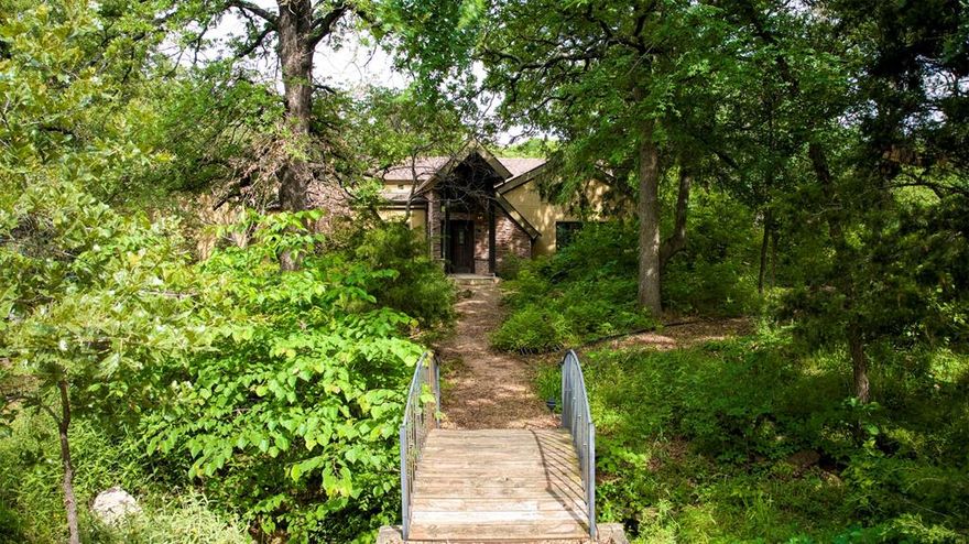 You'll love this spacious home in Oak Point, TX. Nestled on 1.65 heavily wooded acres in the prestigious Emerald Sound community, this custom 4-bedroom, 3-bath estate offers over 4,100 sq. ft. of living space with unlimited potential. Privately situated with a grand bridge walkway entry, the home is surrounded by a state-recognized wildflower landscape & meandering garden paths, creating a serene retreat reminiscent of old-world European charm.
Inside, cathedral ceilings, Tiffany-style lighting, & rich wood flooring set an elegant tone, while natural light pours through expansive windows. The chef's kitchen is appointed with Corian countertops, a large island, & an abundance of built-in cabinetry. The primary suite features a private en-suite with a jetted tub, dual vanities, & custom closet system. Entertain effortlessly with a spacious living and dining area, a screened sunroom, built-in's throughout, & multiple balconies offering peaceful treetop views. The basement includes a bonus room, mudroom, & two additional bedrooms, perfect for guests or multigenerational living.
Additional highlights include a 3-car oversized garage (24x41), central vacuum, propane fireplace, smart layout with dedicated office, and premium features throughout. Enjoy the peace of country living with the convenience of being near Lake Lewisville and top-rated Denton ISD schools. This unique home is ready for you to make it your own.