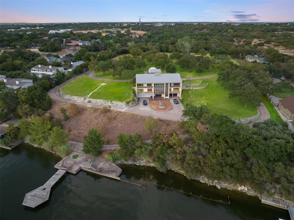 This serene, custom-built estate is privately gated and nestled on nearly 17 acres of picturesque land in Granbury. The property features a stunning park-like drive, winding through natural beauty before opening up into a spacious circular drive leading up to the estate. The estate boasts breathtaking panoramic views of the lake, with nearly 420 feet of pristine waterfront. 

The home welcomes you with a porte-cochère at the entrance. Inside, the foyer opens to a full bar and gathering area, highlighted by a floor-to-ceiling stone fireplace. The expansive living room flows seamlessly into the formal dining room, which connects to the kitchen and breakfast area—all offering spectacular lake views. The kitchen is equipped with high-end stainless steel appliances, including a wine fridge, ice maker, and Subzero refrigerator, as well as a generously sized walk-in pantry and laundry room.

The  primary suite includes a spa-like bath with separate his-and-her sides, with large closets. There is a sitting area leads out to a private balcony. There is a private study, also has balcony access, offers an ideal space for work or relaxation. The second floor features five spacious bedrooms, each with its own ensuite bath, as well as a large family room with captivating lake views. This is also an excellent investment or development opportunity.