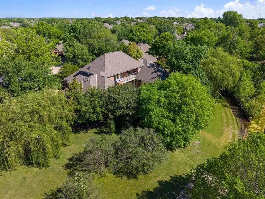 Nestled at the end of a tranquil cul-de-sac, this stunning Steve Roberts custom home offers breathtaking views of a greenbelt, creek, and mature trees. Designed with an exceptional flowing layout, the home features spacious rooms, abundant storage, and gleaming hardwood floors throughout.
The gourmet kitchen is truly a chef’s dream, featuring a built-in Sub-Zero refrigerator, six-burner Viking gas cooktop, double ovens, warming drawer, microwave, and a large island. It may be one of the largest kitchens you will find in a Plano home. A sunny breakfast area invites relaxed mornings, while the adjoining formal living and dining spaces, highlighted by a fireplace, create an elegant setting for entertaining. Just off the kitchen, the warm and inviting den offers custom built-ins, a walk-in wet bar, and a fireplace, making it the perfect place to gather and unwind. A richly appointed study with pocket doors adds sophistication and privacy. The spacious primary suite on the main level includes room for a sitting area, offering comfort and seclusion. Over the past year, the home has been thoughtfully updated with all new Pella windows, fresh paint throughout, and new carpeting, enhancing both comfort and energy efficiency. Additional amenities include a whole-house emergency generator, dishwasher, disposal, and ice maker. Designed for entertaining on a grand scale, this exceptional home has hosted elegant events for more than 80 guests while still maintaining an intimate and welcoming ambiance. Once featured in Plano Profile magazine, this remarkable property combines timeless elegance, unparalleled views, and outstanding convenience. A true haven in the heart of nature.