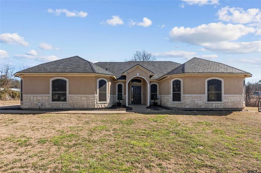Built in 2018 and sitting on a generous one-acre lot in Ben Wheeler, this 4 bedroom, 2 bath home blends modern comfort with the relaxed charm of East Texas country living. You get the space, privacy, and room to breathe, all while staying just a short drive from Tyler’s conveniences! Inside, the 2,368 square foot open floor plan feels bright, functional, and easy to live in. The living, dining, and kitchen flow together seamlessly, making this home ideal for both everyday life and entertaining. The kitchen anchors the space with plenty of room to cook and gather, and it opens to a cheerful breakfast nook that looks out over the backyard, a peaceful spot to start your mornings. All four bedrooms are well sized with great natural light, giving everyone their own comfortable retreat. Recent upgrades throughout add real value and efficiency, including spray foam insulation, new roof shingles, solar screens, a new garage door, and a new front entry door, so this home truly feels move in ready. Outside is where this property really shines. An elegant iron front fence boosts curb appeal and privacy, while the new wooden back deck creates the perfect setting for grilling, relaxing, or even adding a hot tub down the line. With a full acre to work with, there’s plenty of room for a garden, chickens, a shop, or space to play. A built in storm shelter also provides extra peace of mind during Texas weather. If you want the best of both worlds, modern living with room to roam, this Ben Wheeler home delivers. It’s a rare mix of newer construction, thoughtful upgrades, and true East Texas land that’s hard to find at this price point.