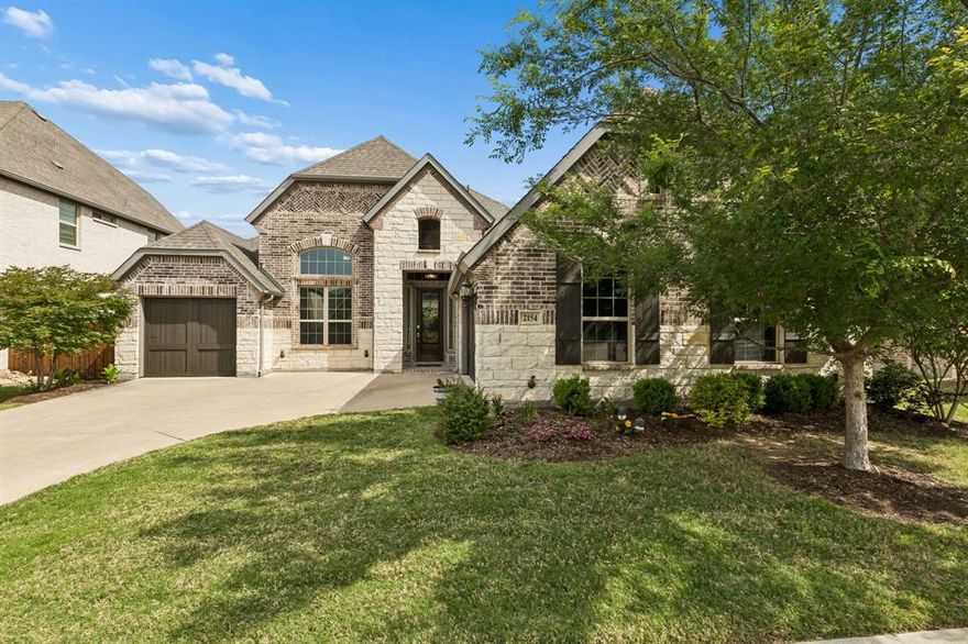 This home blends timeless architecture w-modern comfort, offering a warm yet elevated living experience throughout—and is a rare one-story opportunity on a generously sized lot w-quality finishes throughout. From the exterior, you’re welcomed by a striking combination of brick and stone, accented with rich wood garage doors—creating a strong first impression w-classic curb appeal. Inside, the home opens to thoughtfully designed spaces filled with natural light & architectural detail. The dining area is framed by a dramatic arched opening and complemented by a built-in serving space and wine grotto—perfect for entertaining. The open-concept living room features soaring ceilings, expansive windows, and a beautiful stone fireplace that anchors the space with warmth and character. The kitchen is a true centerpiece, showcasing an oversized island w-seating, custom cabinetry that extends to the ceiling, designer lighting, and stainless steel appliances. It flows seamlessly into the breakfast area and main living space, creating an ideal layout for everyday living & hosting. The primary suite is generously sized with a wall of windows &  tray ceiling detail, offering a peaceful retreat. The spa-inspired bath includes a soaking tub, separate shower, dual vanities, and abundant space to unwind. Three well-sized secondary bedrooms offer comfort and versatility, each featuring ample closet space and easy access to beautifully appointed baths—ideal for family or guests. A dedicated private office provides a quiet & functional space for working from home or a refined study, thoughtfully positioned for both privacy and convenience. In every detail, this home captures effortless luxury and functional design—made even more special by its rare single-story layout on a generous lot. With quality finishes, timeless style, and a layout built for both everyday living and entertaining, this is a home that checks every box and leaves a lasting impression.