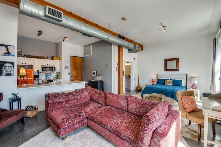 Rare opportunity to own an extensively updated loft style condo, offering East Dallas views through tall windows in a bright and open floorplan with 10' wood-beamed ceiling. The newly remodeled kitchen is the focal point of the open layout that integrates living, dining & kitchen areas. The sparkling kitchen showcases a full Bosch appliance package, gleaming quartz counters, polished concrete floor, and a custom tile backsplash. The home is brightly lit with morning sun but can be darkened with remote controlled solar powered blinds along the wall of oversized windows. The generous open plan living area has polished concrete floors and enjoys expansive views as you look down on the city below. The bath has been updated with a spa-like frameless glass shower enclosure and chrome rain spray head, ceramic floors, granite counters and upgraded cabinetry. Other amenities include a walk-in closet, exposed ducts, exposed wood beams & columns, secure entry garage with assigned parking, a fitness center, landscaped private courtyard swimming pool, and a great downtown location convenient to everything. Retro refrigerator, Washer & Dryer are negotiable.  Most furniture & decor available for separate purchase.