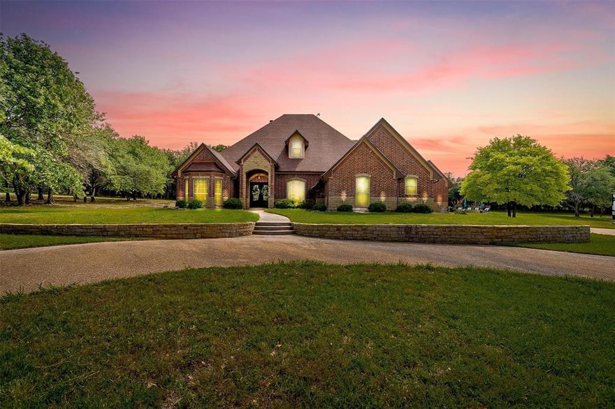 Experience refined Texas ranch living on 4+ private, tree-covered acres inside a gated community in sought-after Peaster ISD. This custom-built, extensively remodeled estate blends luxury finishes, thoughtful design, and everyday functionality with wide-open space and resort-style amenities. The open-concept layout showcases soaring ceilings, rich hardwood floors, custom millwork, and expansive windows that flood the home with natural light while framing peaceful acreage views. The chef’s kitchen is designed to impress and perform, featuring a Taj Mahal quartzite countertops from Brazil, gas cooktop, double ovens, built-in refrigerator, brick architectural accents, custom cabinetry, and abundant prep space—ideal for hosting, gathering, and entertaining. The private primary retreat offers a spa-inspired bath, separate shower, and generous walk-in closet. Three additional bedrooms, 2.5 baths, and an upstairs game room provide flexibility for media, fitness, work-from-home, or guest space. A dedicated Doggy Suite adds a thoughtful touch for pet lovers. Step outdoors to your backyard retreat complete with covered living area, wood-burning fireplace, beach-entry pool, spa, and generous patio space for entertaining. Enjoy your seasonal private pond, horseback riding, gardening, wildlife watching, and unforgettable sunset views. Equestrian-friendly acreage offers room to roam, ride, and expand. The 40x60 shop is plumbed for a bathroom and has its own aerobic septic system—ideal for a home business, hobby space, gym, or future conversion. A massive 60x40 barn adds additional storage, livestock capability, or guest quarters potential. Gated entry. Mature trees. Expansive driveway. Peaceful country setting with convenient access to town. Luxury, privacy, and versatility—this is Texas living at its finest.