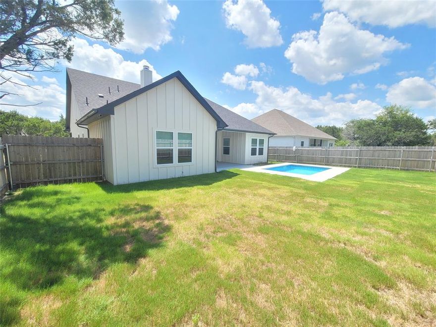 Welcome to this beautiful Granbury home that perfectly blends comfort and style. Home was built and sold as a new construction over one year ago. Sellers only lived in home for a short time had to relocate for work purposes to another city. Features in this home has a spacious 36-inch stainless steel stove for those gourmet chefs and glass hood range over and microwave is in separate cabinet from the stove. Includes a stainless steel fridge with purchase of the homes already so you can start meal prepping after you move in and cook those home cooked meals. Kitchen has a pot filler, custom backsplash, designer lightning, white shaker cabinets self closing with hardware, white quartz countertops.  Amazing place to start or already a social media influencer for making recipes videos in kitchen. High ceilings throughout home, living room has a unique design for tray ceilings, cozy wood burning fireplace create an inviting interior with open concept kitchen and living room space. Step into after a long day in a spa feeling en-suite bathroom, soak in lovely bubble bath in soaking tub, surrounded with cozy and neutral clean feel, custom glass shower, glowing white tile design match with double vanity sinks, and designer mirrors. Primary bedroom has high cathedral ceilings, barn door with backdoor entrance to back patio. Hallway bath is cute as can be with double vanity sinks for more separate space and plenty of cabinet storage. Entrance hall has chandelier shining so bright and crystals hanging to give that huge welcome wow feeling walking inside the house. While the charming covered front porch add curbs appeal with wooden swing to enjoy reading a book or have your morning coffee. Step out back to enjoy the covered back porch overlooking a refreshing cocktail swimming pool, perfect for those super hot Texas summers.  This thoughtfully designed property offers the ideal balance of indoor and outdoor living space. Schedule an appointment for yourself to see rest of home.